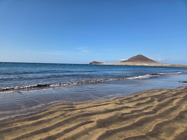 Vista panorámica de Playa El Médano con la Montaña Roja al fondo durante la marea baja.