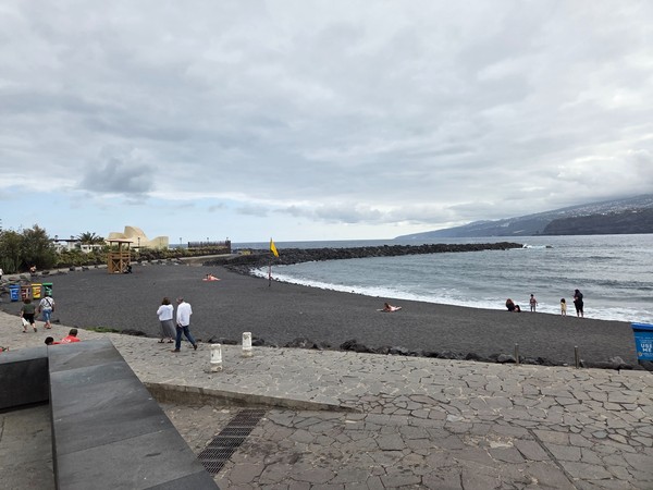 Playa Martiánez con bandera amarilla y rompeolas que protege la bahía.
